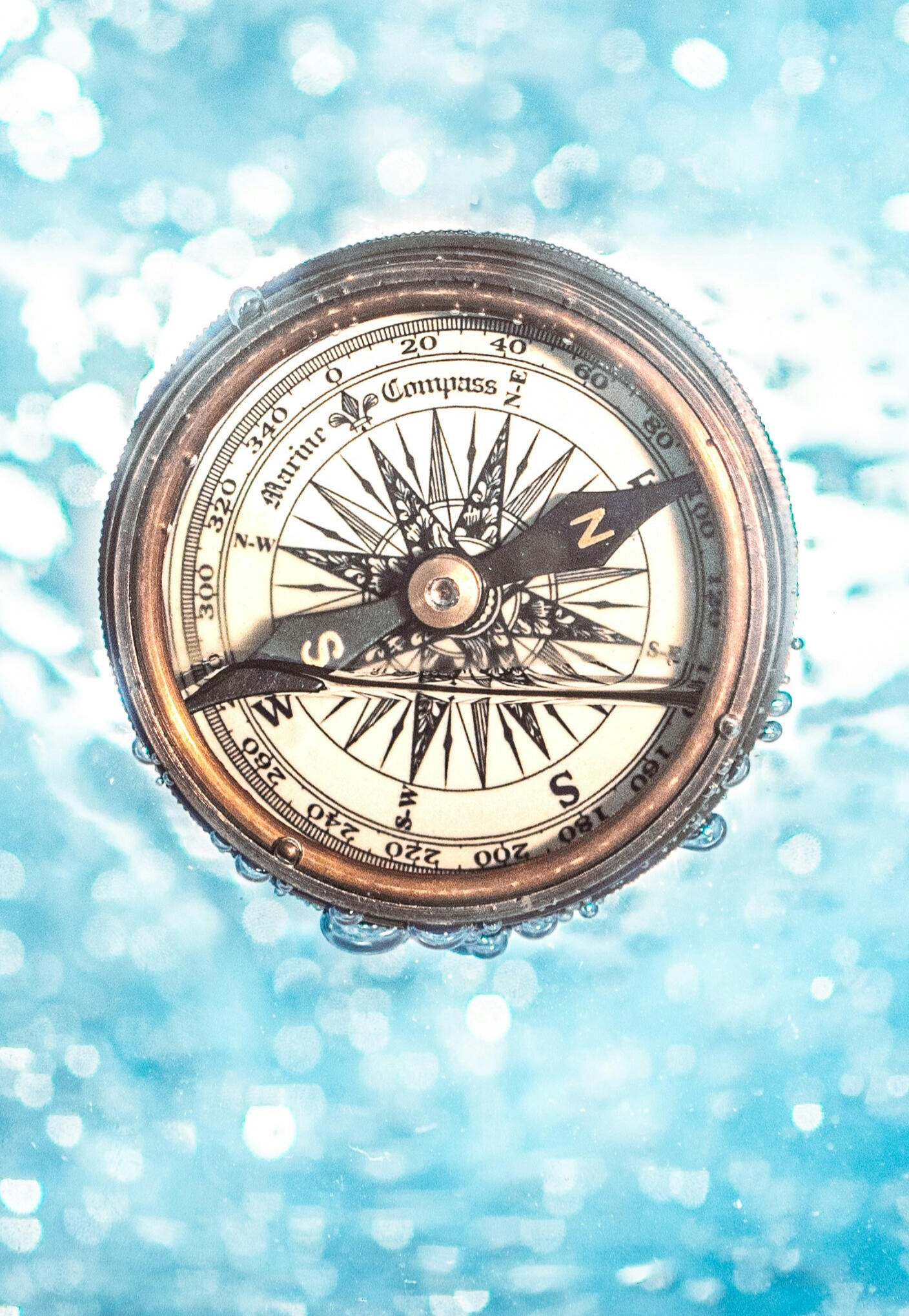 Compass immersed in clear blue water